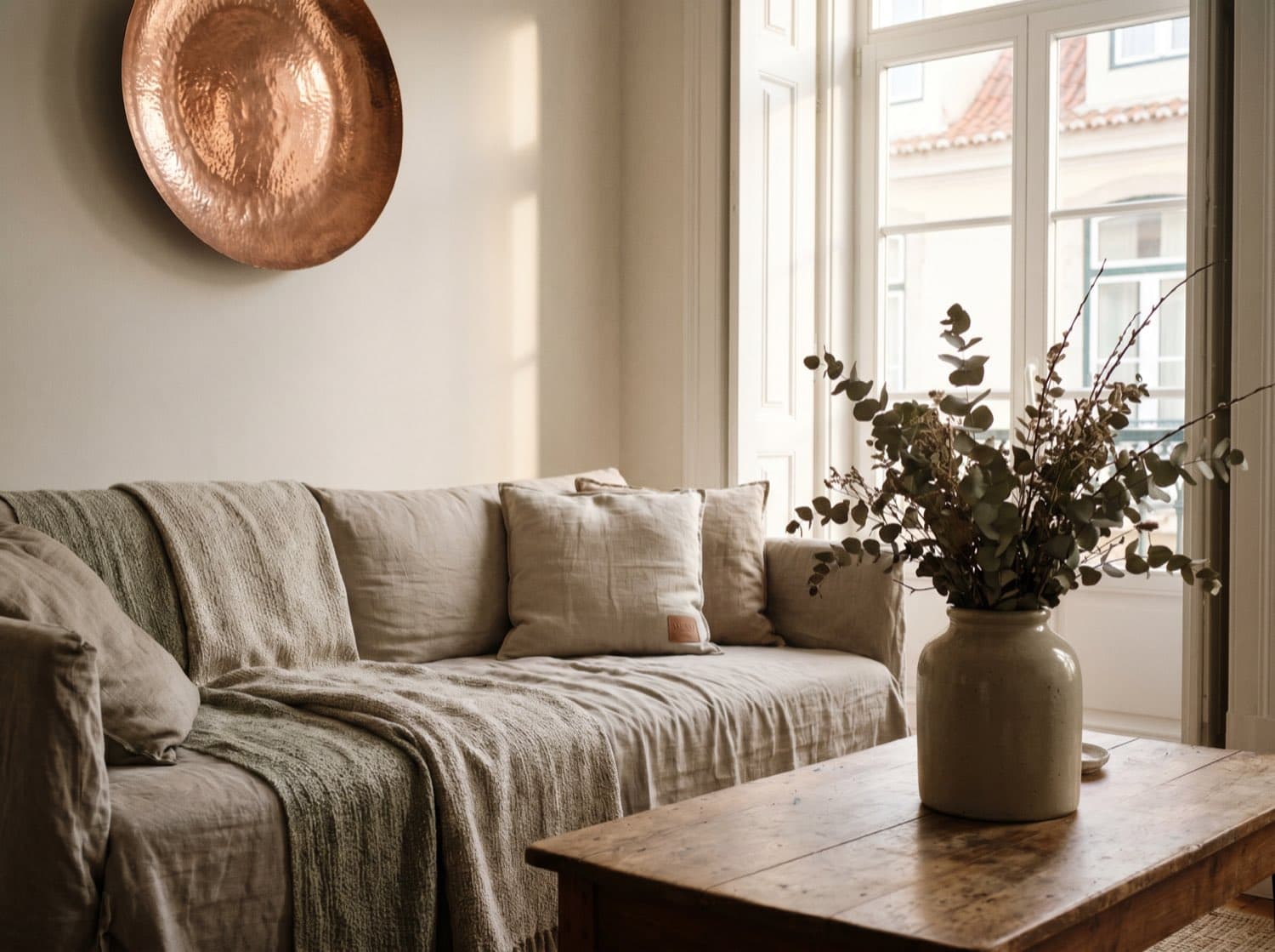 Lookbook-Bild 4 — Wohnzimmer mit Leinen-Sofa, Kupfer-Wandobjekt und Steinzeug-Vase